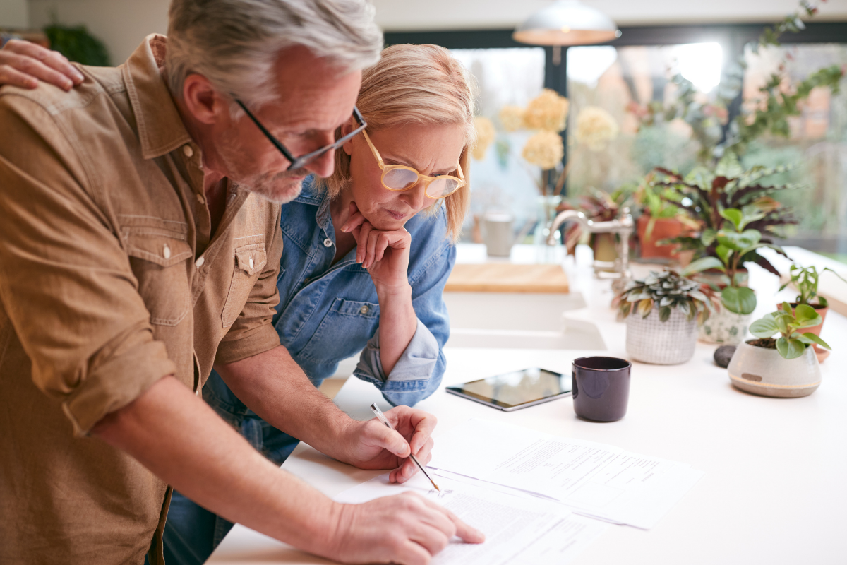 Retired couple reviewing financial paperwork together, symbolizing prudent retirement planning and protecting income from rising costs.
